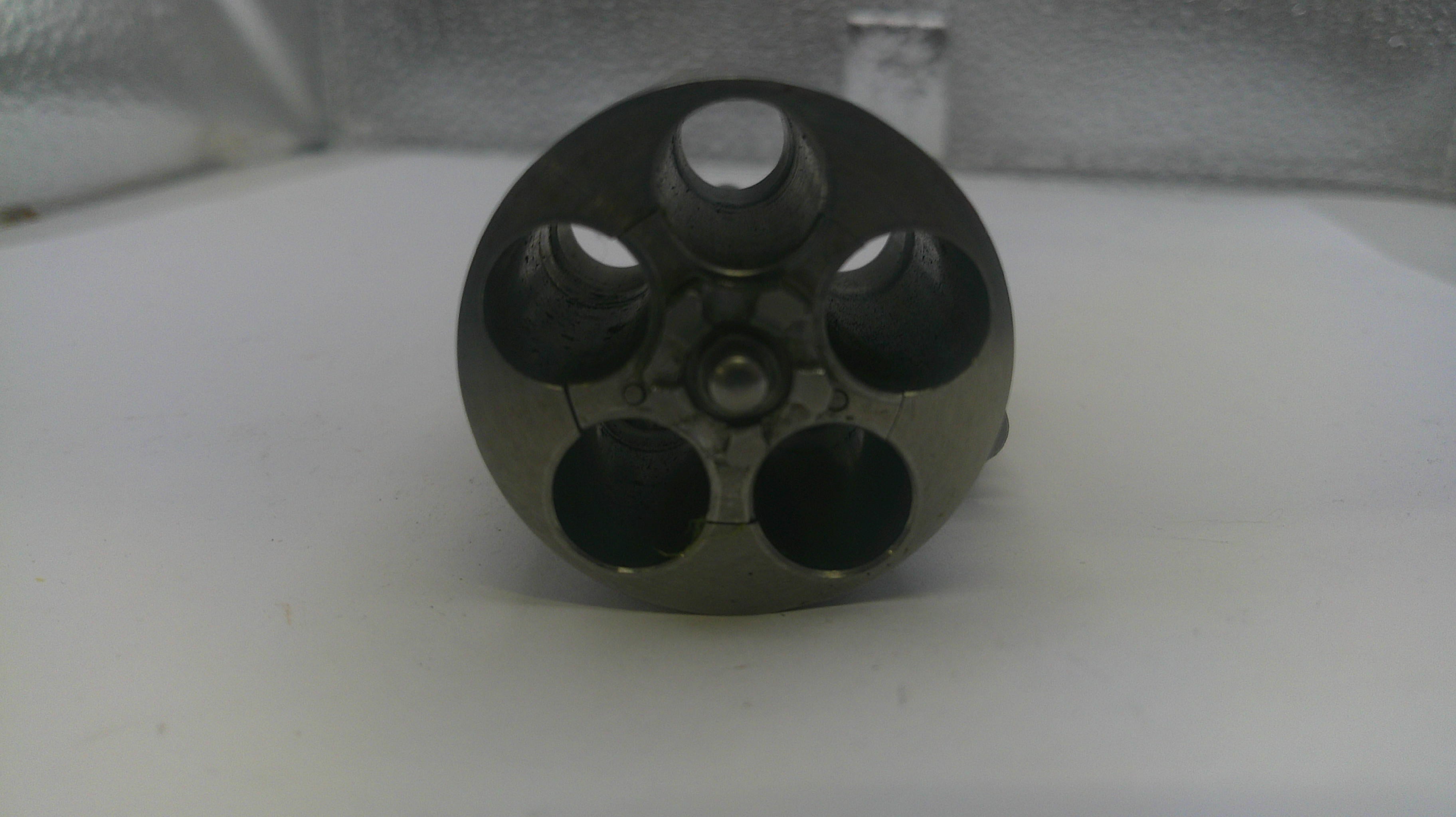 Metallic cylindrical object with multiple holes on a white surface