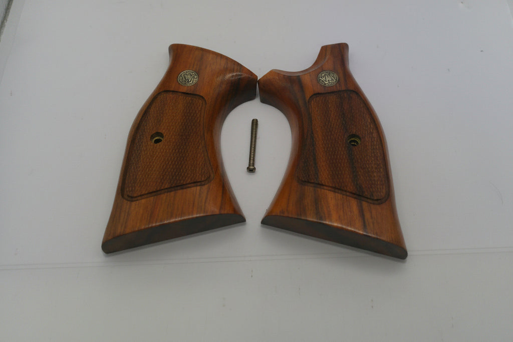 Two wooden gun grips with a small metal screw on a white surface
