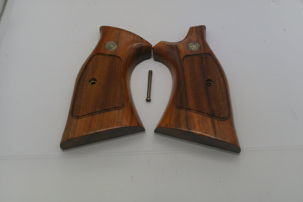 Two wooden gun grips with a small metal screw on a white surface