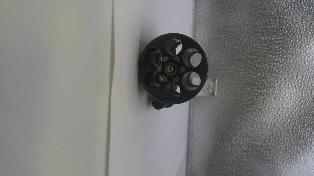 Black circular object with multiple holes on a textured surface