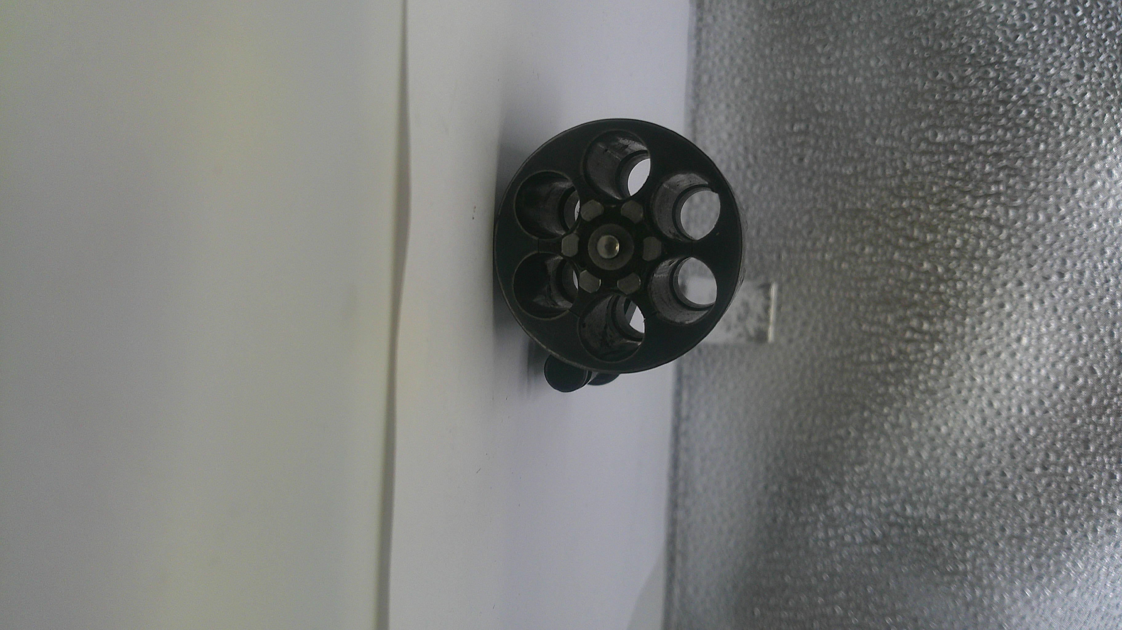 Black circular object with multiple holes on a textured surface