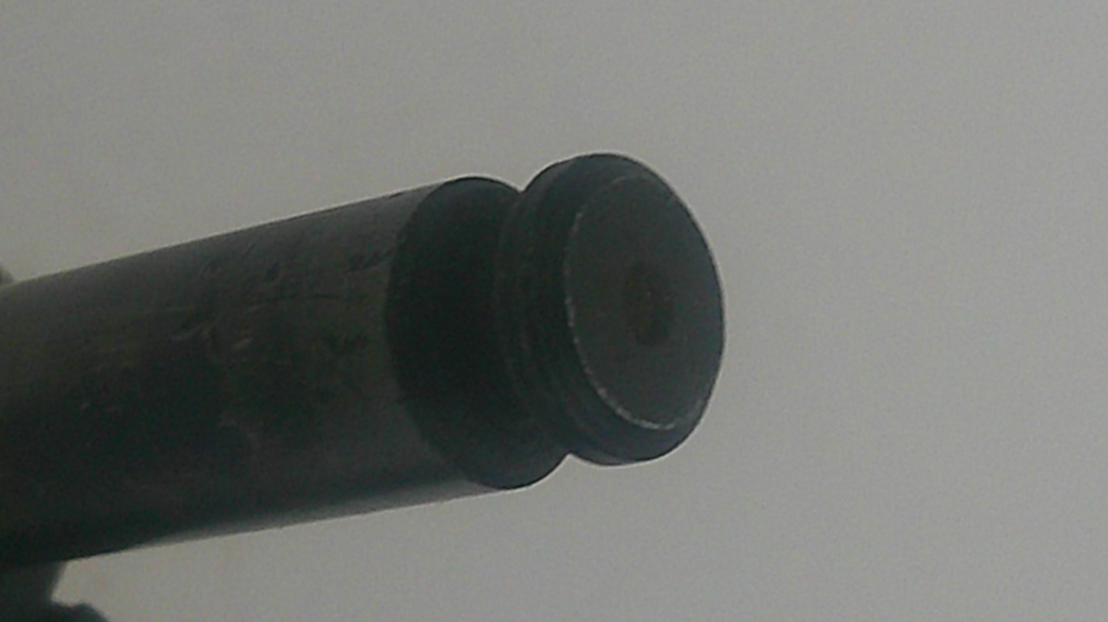 Close-up of a black cylindrical object on a light gray background