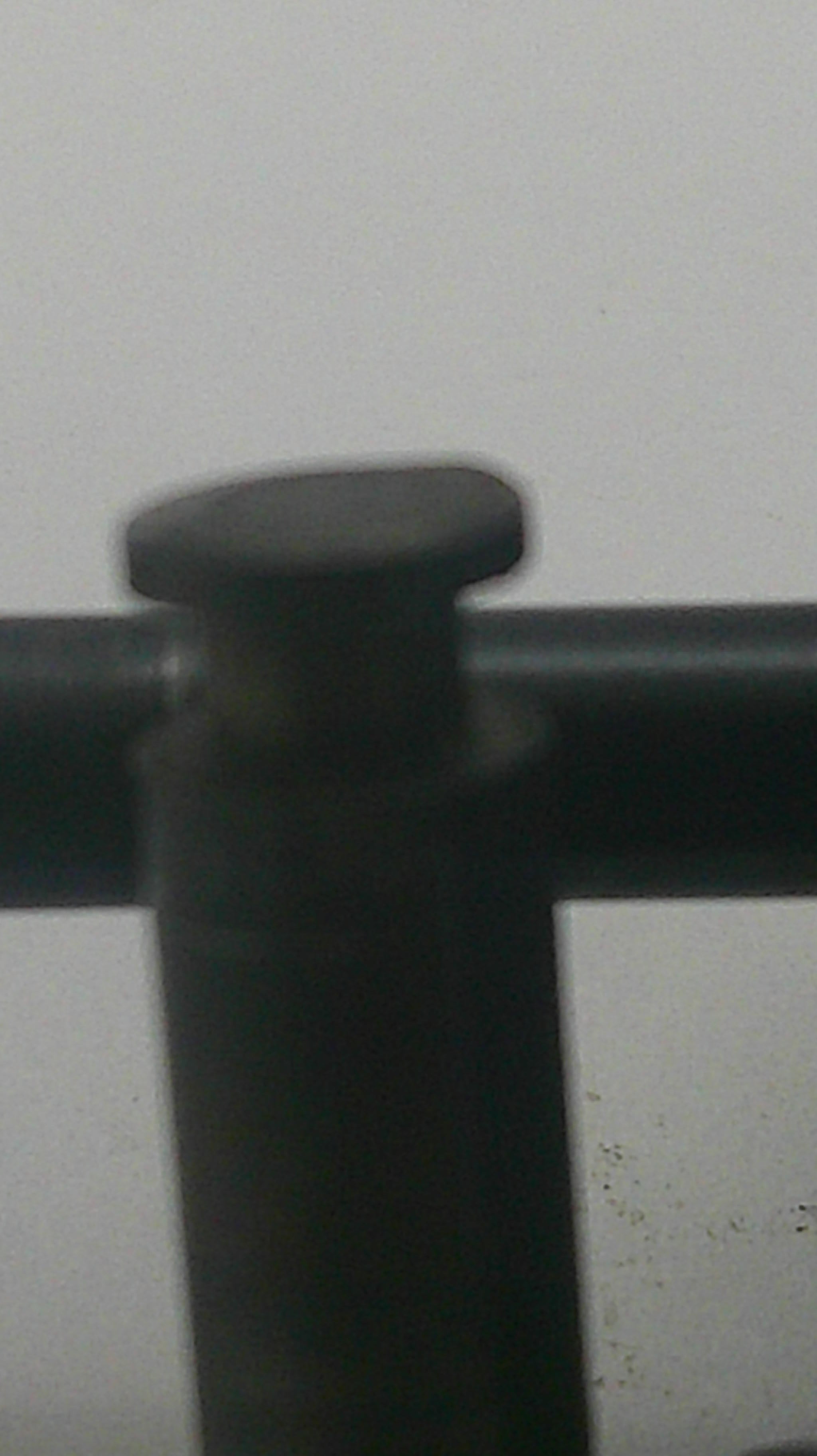 Close-up of a black metal frame corner with a round knob, set against a plain light gray wall.
