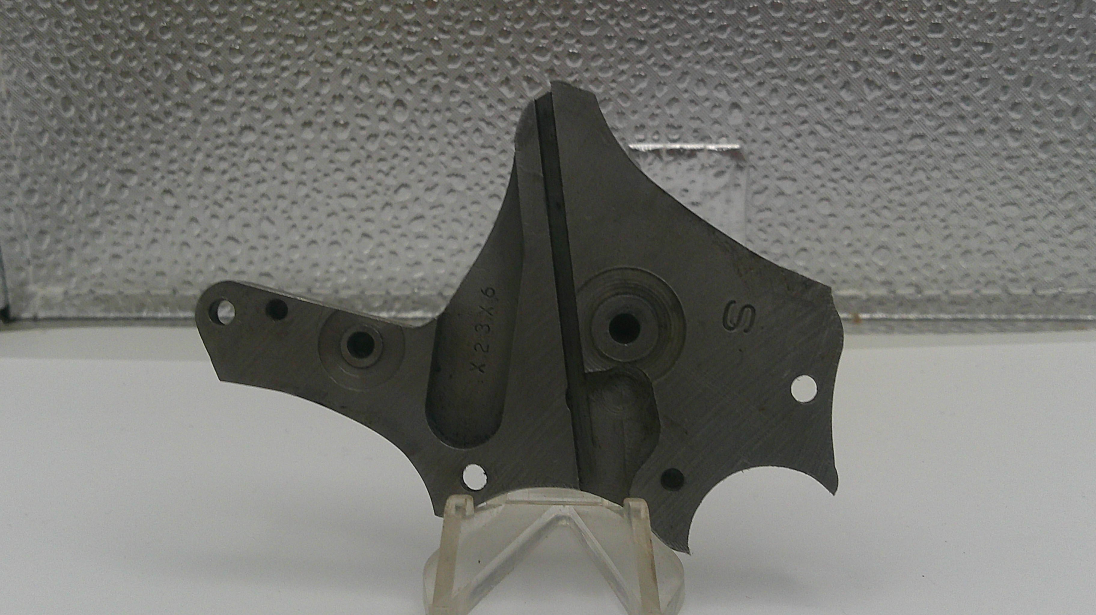 Black metal component on a stand with a textured gray background