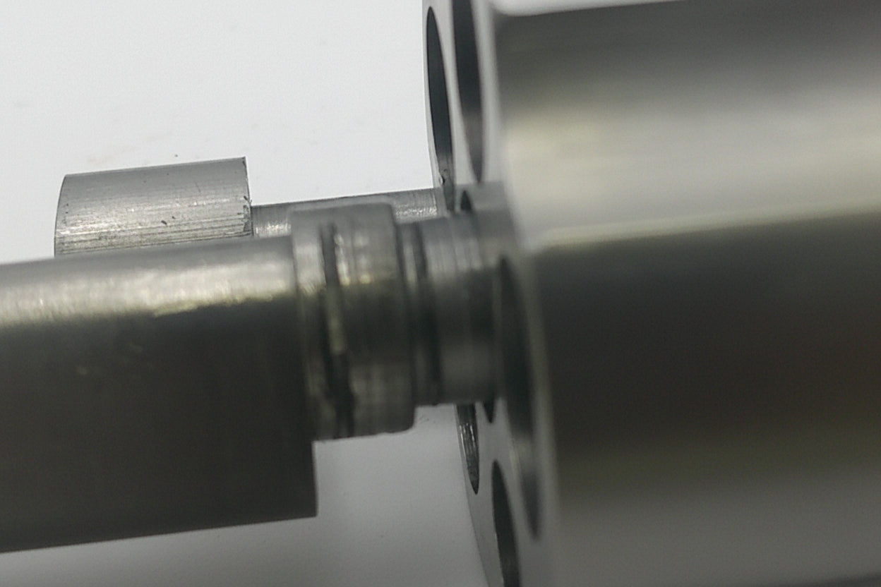 Close-up of a metal cylindrical component with a smaller cylindrical object inside on a light gray background.