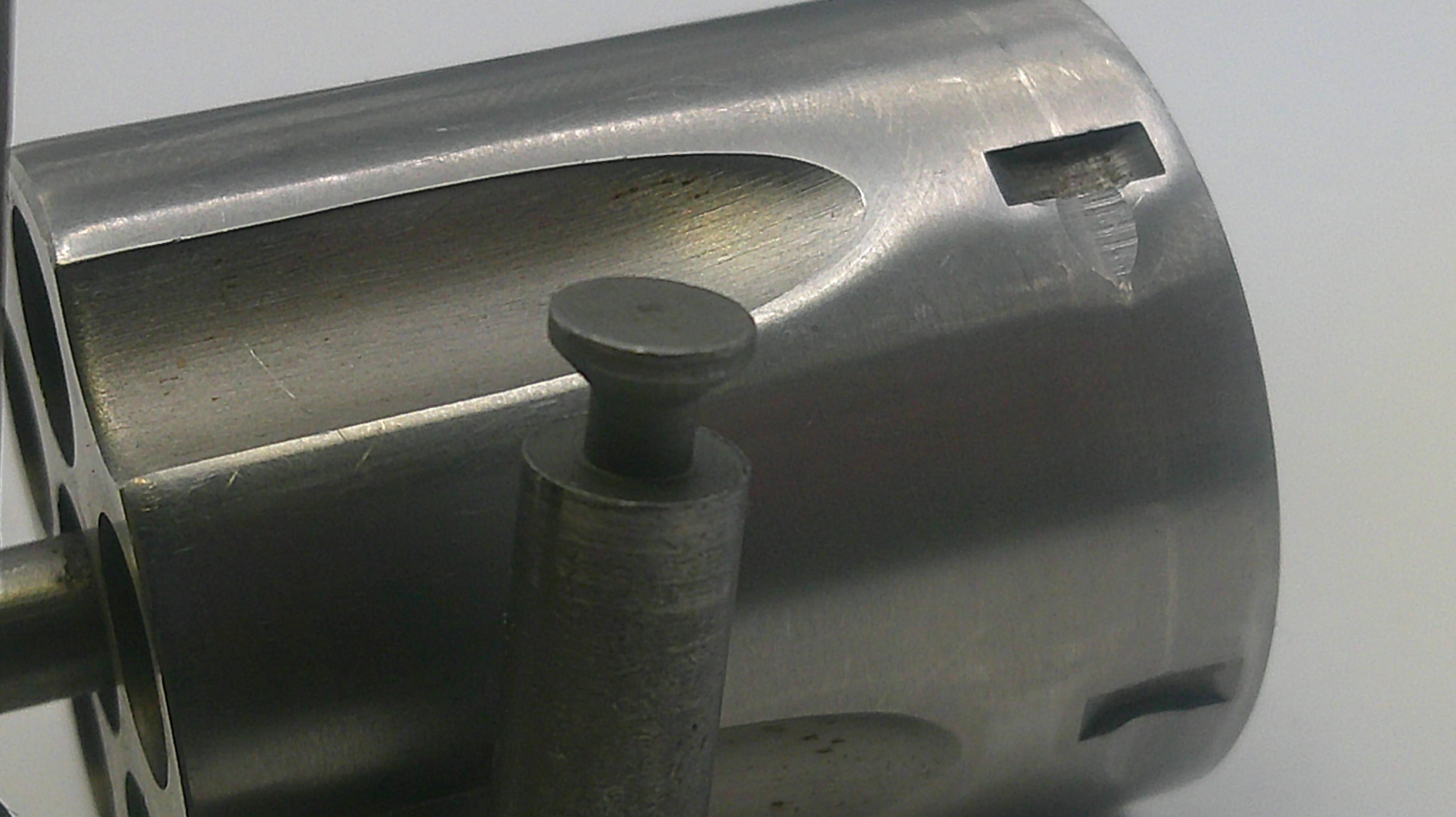 Close-up of a metallic cylindrical object with a central rod on a light gray background