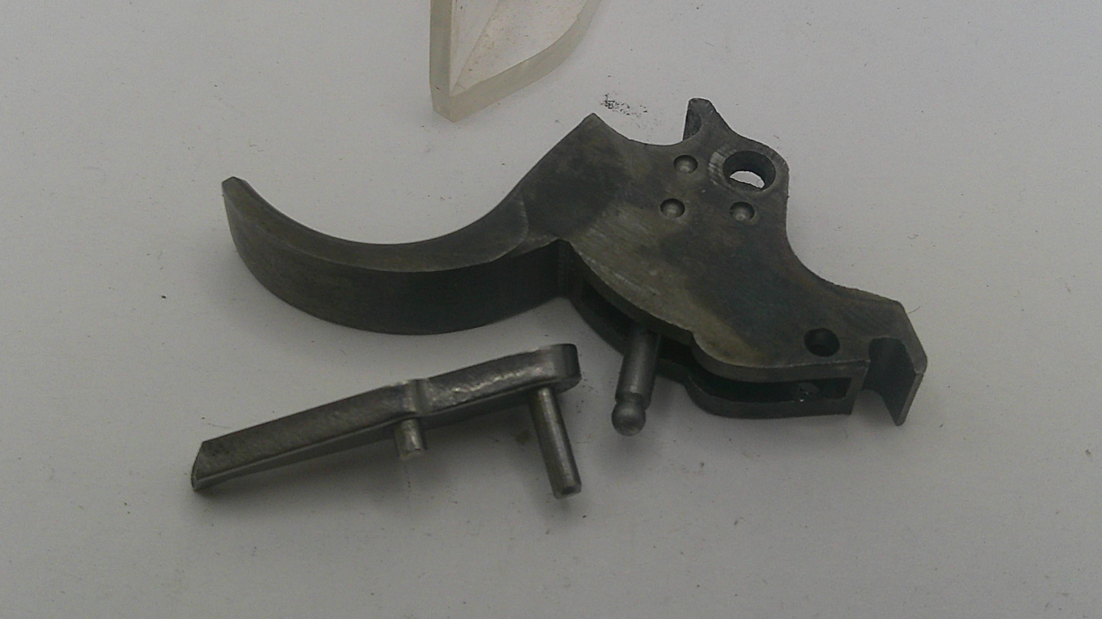 Two metallic gun parts on a white background