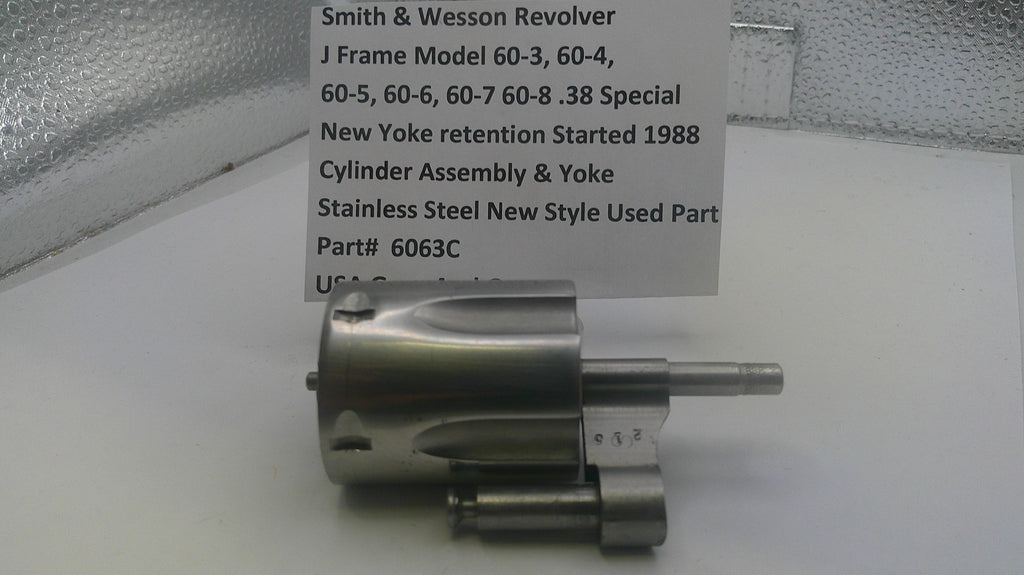 Smith & Wesson revolver cylinder assembly on a white surface with a descriptive card.