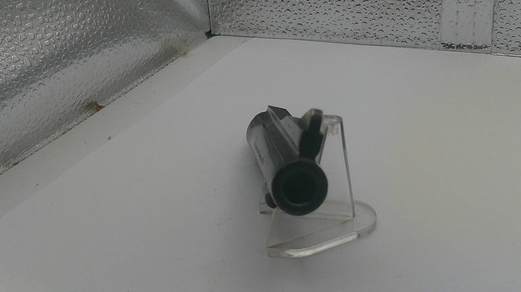 Clear plastic stand with cylindrical object on a white surface