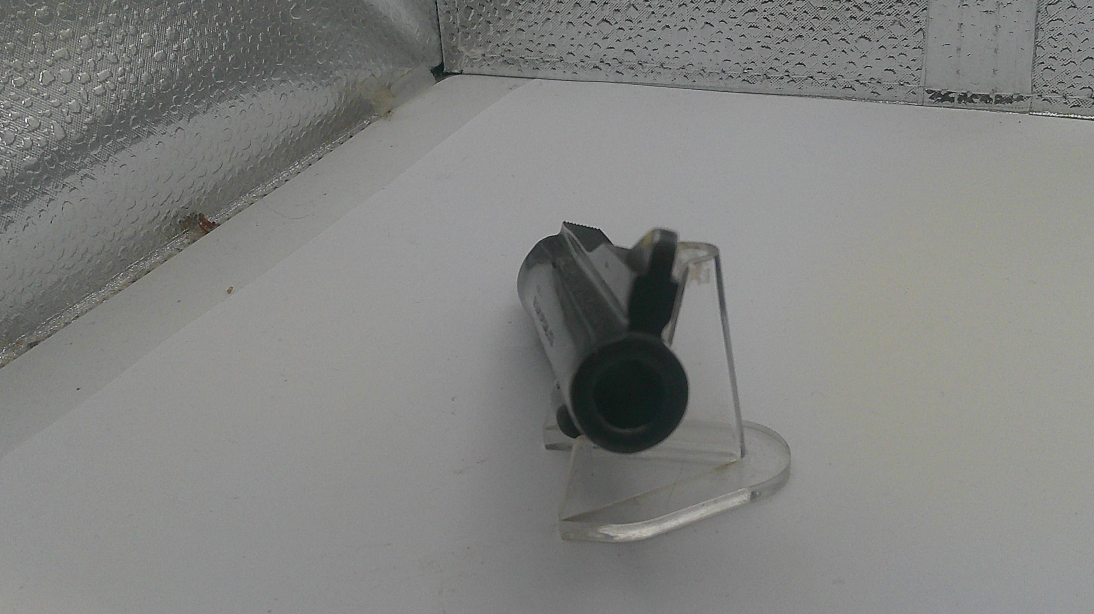 Clear plastic stand with cylindrical object on a white surface