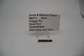 A photo showing a Smith & Wesson M&P9 9mm trigger pin used replacement part, displayed on a stand with product information sign.