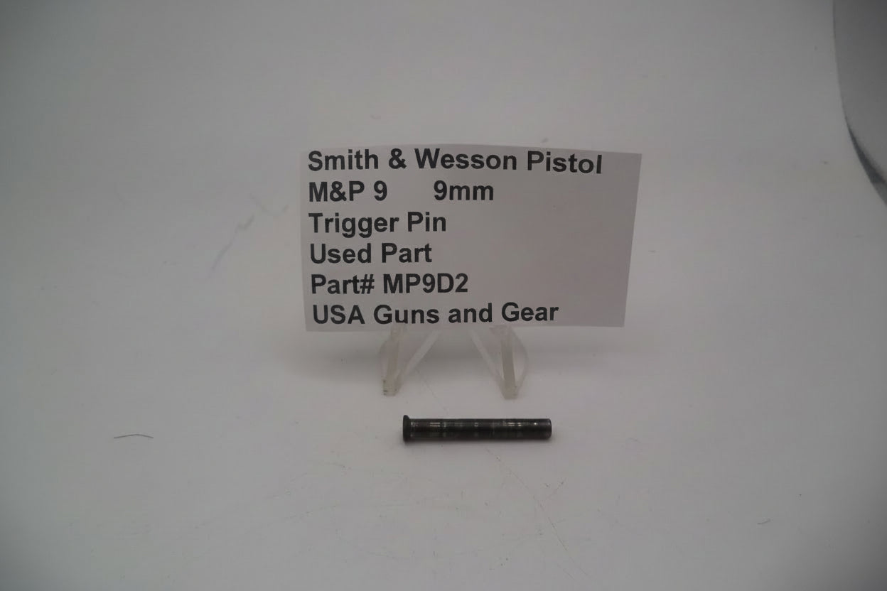 A photo showing a Smith & Wesson M&P9 9mm trigger pin used replacement part, displayed on a stand with product information sign.